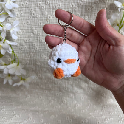 Porte-clés poussin blanc en crochet artisanal vu de trois quarts, mini amigurumi doux avec bec et pattes orange.